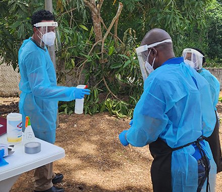 Three people doffing PPE outside. 