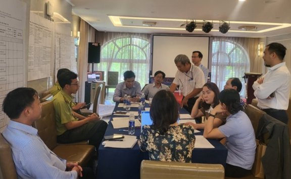 Lively group discussion during the training, between a group of participants, while sitting at a long table.