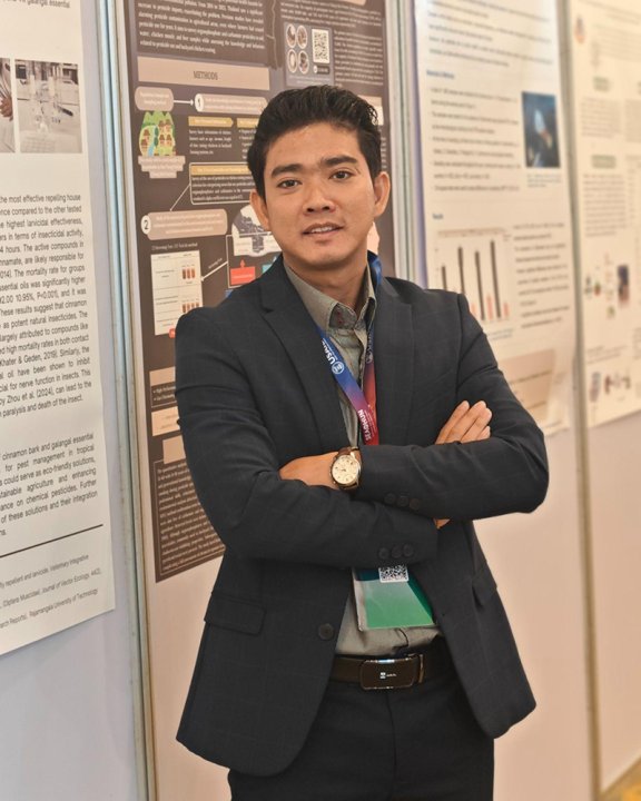 Mr. Chan standing in front of a wall of posters, directly in front of a poster from a colleague.